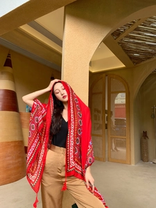 Detail of red ethnic print shawl with fringe tassels for desert beach travel photos
