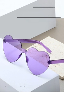 Detailed close-up of fashion purple heart-shaped rimless sunglasses on a white stone base
