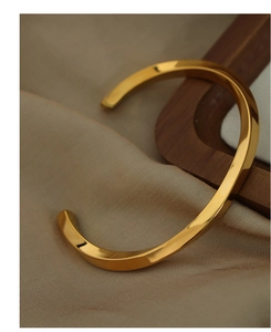 Detail of twisted gold-plated titanium steel bracelet on elegant silk background