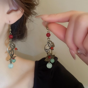 Détail de boucle d'oreille fleur à pompon avec agate rouge et jade vert sur mannequin