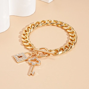 Close-up of golden Cuban chain with rhinestone encrusted lock and key charms with OT clasp