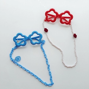 Detail view of flower-shaped kids sunglasses in blue and red with decorative chain straps