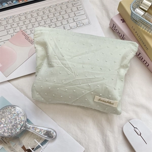 Detailed texture of green floral vanity bag with brand label on a desk setup