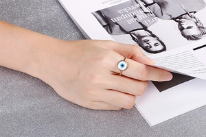 Rose gold evil eye ring with blue and white nazar charm shown on a model's hand