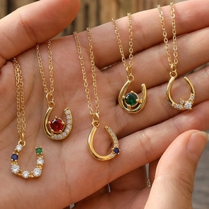 Detailed close-up of U-shaped horseshoe necklaces with colorful zircon stones in gold