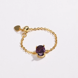 Detail of adjustable gold-plated chain ring with oval purple zircon and heart charm