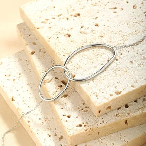 Detailed view of silver double oval pendants on textured stone background for a chic look