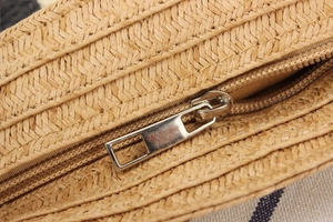 Detailed macro view of woven paper rope texture with a golden zipper pull on a straw bag