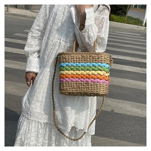 Rainbow striped straw tote bag worn as a crossbody bag with white polka dot dress