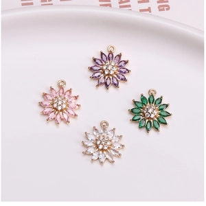 Detailed view of colorful daisy pendants with zircons and gold-plated bails for DIY jewelry