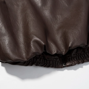 Detail of dark brown leather jacket hem showing elastic cuff and stitching quality