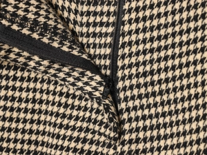 Macro detail of high-quality houndstooth fabric with a smooth black nylon zipper closure