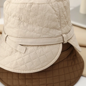 Detail of quilted texture and fine stitching on beige and brown bucket hats