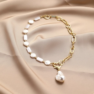Detail of baroque pearl necklace with gold chain, heart clasp, and large pearl pendant
