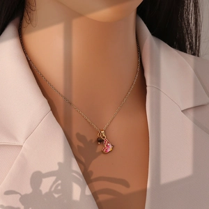 Detail of a gold butterfly necklace with red enamel and dark bead worn on a beige blazer