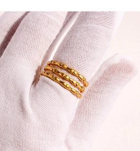 Detail of three layered golden rings with bamboo texture on white gloved hand