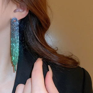 Detail of elegant gradient blue and green rhinestone tassel earrings on a model