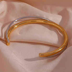Detail of interlocking gold and silver rings on elegant beige satin fabric texture