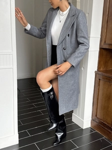 Full body view of grey double-breasted wool coat styled with black tall leather boots