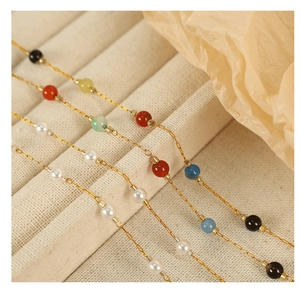 Detail view of gold beaded necklaces with white pearl and colorful accent beads