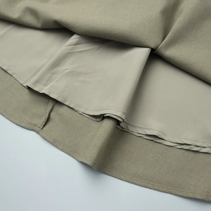 Detail view of double-layered sage green skirt hem with textured linen-blend fabric
