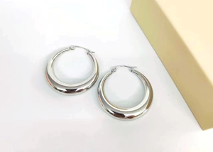 Macro detail of silver thick hoop earrings with a high-polished metallic mirror finish