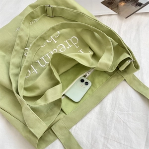 Detail showing the inner pocket of the avocado green canvas tote with a smartphone