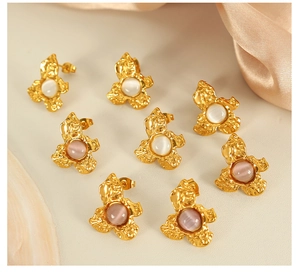 Detail of gold floral earrings with cat eye stone in white and purple finishes