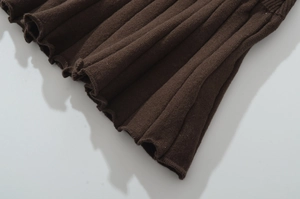 Close-up of dark brown ribbed knit fabric featuring delicate ruffled lettuce edges