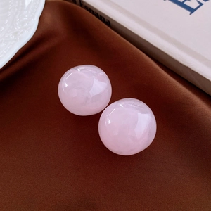 Detailed macro view of two translucent pink resin sphere earrings on a satin fabric