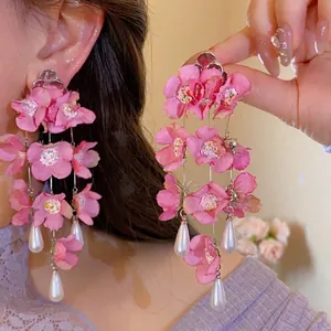 Detailed close-up of pink fabric flower tassel earrings with white teardrop pearls