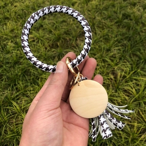 Close-up of houndstooth PU leather wristlet keychain with wooden pendant and gold clasp