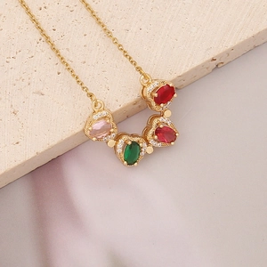 Golden necklace with four colorful heart pendants on beige stone and silk fabric