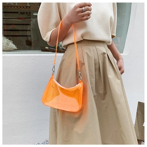 Close-up of vibrant orange transparent PVC shoulder bag with silver metallic buckle