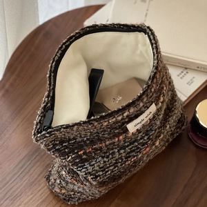 Retro multi-color tweed makeup bag with zipper closure on dark wooden tabletop