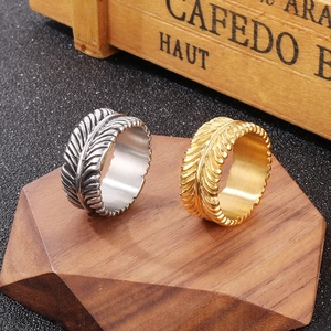 Close-up of gold and silver feather rings with intricate textures on wooden stands