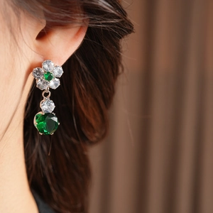 Detail of flower earrings featuring cubic zirconia and faceted deep green gemstones