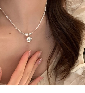 Close-up of 2025 heart pendant necklace with silver beads on a woman's neck