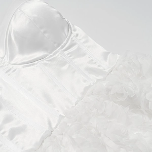 Detail of white corset dress featuring boning structure and 3D floral lace appliqué