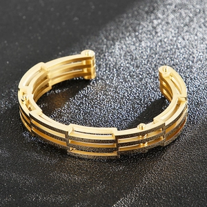 Detailansicht eines goldenen Titanstahl-Armreifs mit Nieten im Rock-Stil und Texturen