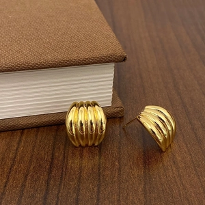 Detail of vintage gold textured stud earrings resting on a wooden table with a book