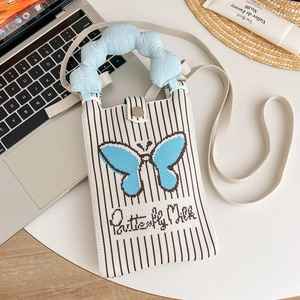 Dettaglio di una borsa a tracolla in maglia con farfalla pixel blu e manico a forma di nuvola