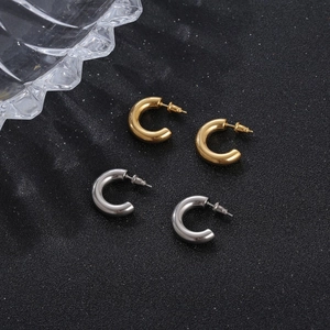 Thick C-shaped chunky hoop earrings in gold and silver finish for women on black surface