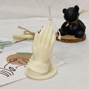 Off-white prayer hand gesture scented candle on a minimalist decorative table setting