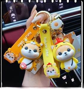 Detail of Fortune Shiba keychain featuring silicone tiger and chicken dragon dolls on a car dashboard