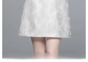Détail de robe trapèze blanche en jacquard montrant le tissu texturé et la coupe courte