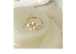 Macro detail of elegant pearl ring cluster on a minimalist green stone display stand