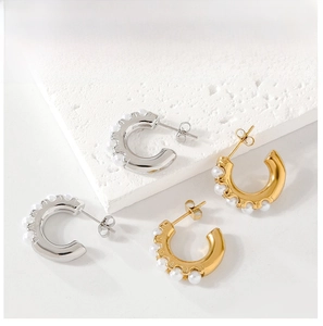 Detailed view of C-shaped earrings with inlaid pearls in gold and silver finishes