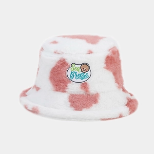 Detail of plush bucket hat featuring pink cow print and Sea Breeze embroidery patch