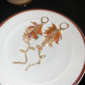 Macro detail of Bohemian crystal tassel earrings on white ceramic dish with golden chains
